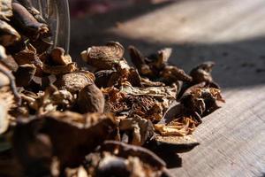 champiñones secos esparcidos con frascos sobre una mesa de madera. foto