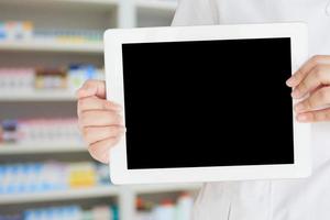 farmacéutico que muestra una tableta digital en blanco en la tienda de farmacia foto