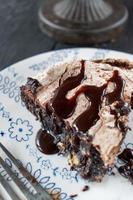 rebanada de postre de brownie al horno cubierto con merengue y remolinos de chocolate y rociado con sirope de chocolate