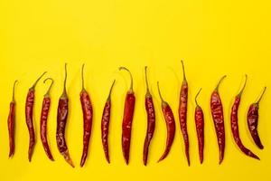 Red Chile de arbol chilis layed out as pattern on fun vibrant yellow background