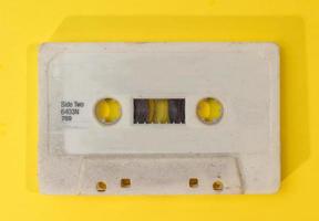 vieja cinta de casete retro con etiqueta grunge sobre fondo amarillo plano foto