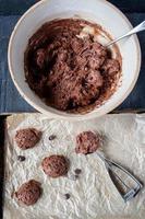 scooping out chocolate chip cookie dough batter onto wax paper cookie sheet flat lay photo