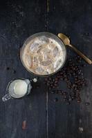 iced coffee with cream on rustic table with raw coffee beans photo