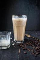 iced coffee with cream on rustic table with raw coffee beans photo