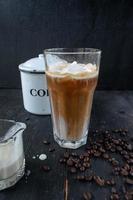 iced coffee with cream on rustic table with raw coffee beans photo