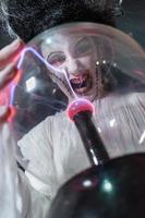 foto de estudio retrato de una joven disfrazada de halloween, cosplay de la aterradora novia de frankenstein posando con una bola de rayos de cristal