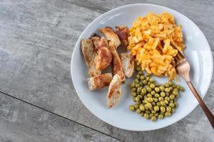 plate of chicken, peas and macaroni and cheese meal flat lay photo