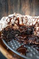 rebanada de postre de brownie al horno cubierto con merengue y remolinos de chocolate y rociado con sirope de chocolate