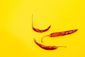 Red Chile de arbol chilis layed out as pattern on fun vibrant yellow background