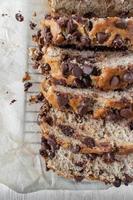 sliced chocolate chip banana bread loaf on wax paper flat lay photo