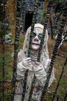 retrato de un joven disfrazado de halloween, cosplay de una momia aterradora en la cerca del cementerio foto