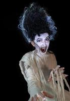 studio shot portrait of young girl in costume dressed as a Halloween, cosplay of scary bride of Frankenstein pose on isolated black background photo