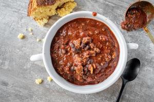 bowl of chili with black beans and cornbread flat lay photo