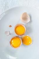 group of egg yolks in broken shells on white background flat lay