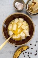 Mixing bananas and eggs in large rustic bowl for banana bread flat lay photo