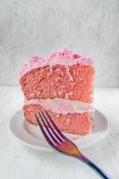 rebanada fina festiva de pastel de cumpleaños rosa con flores de hielo y vista lateral del tenedor foto