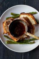 gravy ladle with beef stock over Yorkshire pudding with beef and asparagus photo