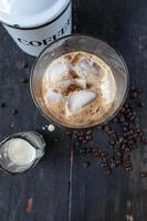 iced coffee with cream on rustic table with raw coffee beans photo