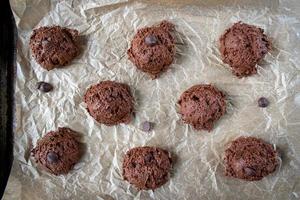 scooping out chocolate chip cookie dough batter onto wax paper cookie sheet flat lay photo