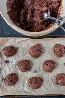 scooping out chocolate chip cookie dough batter onto wax paper cookie sheet flat lay photo