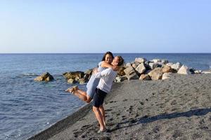 Young couple fooling around on the background of the sea. Shot on Santorini Beach. photo