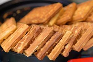 Close up of rustic traditional waffle at street food festival. Outdoor cooking service gastronomy and takeaway food concept photo