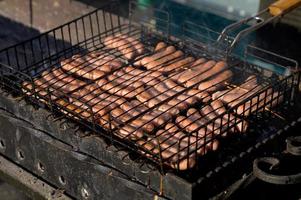 Grilled sausage with the addition of herbs and vegetables on the grill plate, outdoors. Grilling food, bbq, barbecue photo