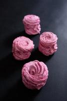 Homemade pink marshmallow on a black background. Top view photo