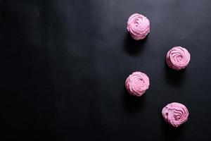 Homemade pink marshmallow on a black background. Top view photo