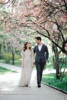 Beautiful happy bride and groom being showered with confetti from cherry blossoms photo