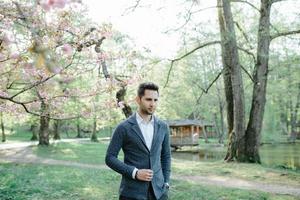 Portrait of young trendy man, suspenders and bow-tie on gray background. photo