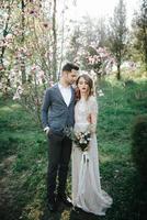 Sunshine portrait of happy bride and groom outdoor in nature location at sunset. Warm summertime photo