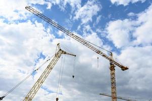 grúas de construcción contra el fondo de un cielo azul con nubes. foto