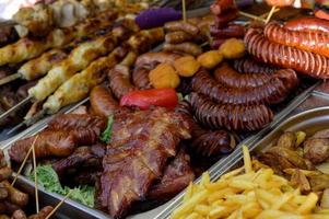 salchicha a la parrilla con la adición de hierbas y verduras en el plato de parrilla, al aire libre. comida a la parrilla, barbacoa, barbacoa foto