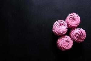 Homemade pink marshmallow on a black background. Top view photo