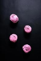 Homemade pink marshmallow on a black background. Top view photo