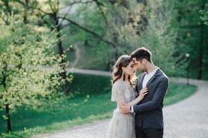 couple in wedding attire with a bouquet of flowers and greenery is in the hands against the backdrop of the field at sunset, the bride and groom photo