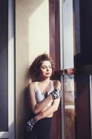 sports curly woman standing at the window photo