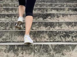 Female runner athlete going up stairs doing cardio sport workout. photo