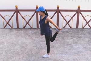 Female fitness doing stretch exercising after workout outside by the lake. photo