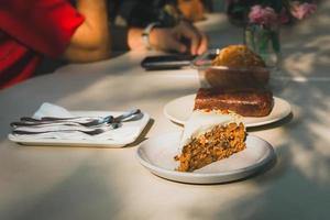 rebanada de pastel de zanahoria en la mesa con una mujer de fondo en un café. foto