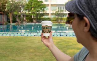 Hua Hin Thailand 13 Mar 2022 - Woman holding Starbuck take away coffee cup on vacation. photo