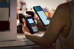 mujer cliente escaneando el código qr en el pago del terminal para pagar la factura con un teléfono inteligente. foto