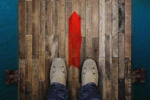 Top view of man standing near the red arrow on old bridge wood floor background. photo