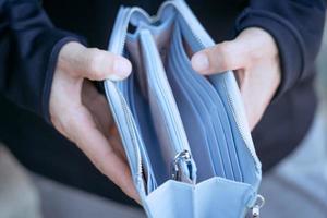 Close-up of blue empty wallet in hand due to the effects of unemployment. photo