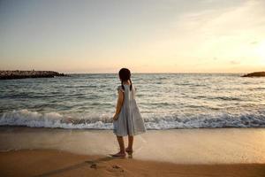 girl children standing at sea beach against beautiful sunset light photo