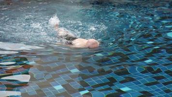 älterer Mann, der während der Sommerferien im blauen Pool schwimmt