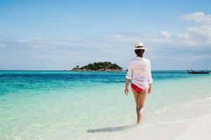 mujer relajante caminando por la playa en isla tropical. foto