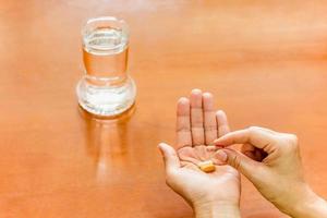 Woman hand holding medicine pills with glass of water. photo