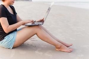 Lifestyle woman freelancer working on laptop computer on a beach.